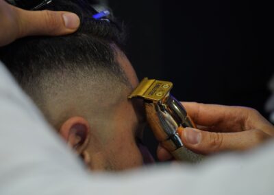 Close-up of a barber using an electric razor for precise grooming on a client's temple.