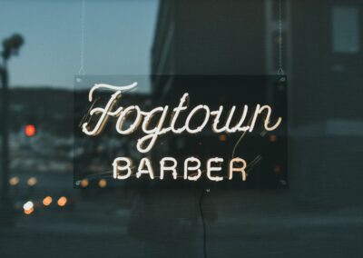 Close-up of Fogtown Barber neon sign in urban setting, exuding a retro vibe.