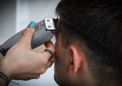 Detailed view of a haircut in progress with electric clippers and stylist's hand.