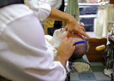 A traditional barber giving a straight razor shave to a man in Buenos Aires, Argentina.