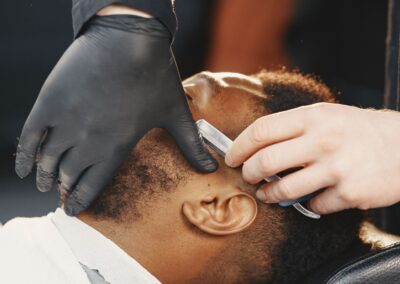 Barber skillfully using a razor to shave a client's beard with precision and care.